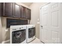 Functional laundry room equipped with a washer, dryer, upper cabinets, and a convenient folding shelf at 6024 Glenmore Garden Dr, Charlotte, NC 28270