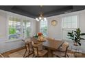 Dining room with a stylish light fixture, large windows, and a wooden table with six chairs, and dark ceiling at 8008 Hudson Mill Dr, Waxhaw, NC 28173
