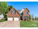 Two-story brick home boasts a well-maintained lawn, attached garage, and classic architectural details at 1050 Merrywood Dr, Newton, NC 28658