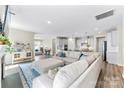 Bright, open-concept living room with plush seating, wood floors, and seamless flow to the kitchen and dining area at 15710 Oleander Dr, Charlotte, NC 28278