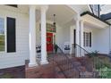 Welcoming front porch with white columns, a red door with a wreath, and rocking chairs at 16610 Blackberry Hills Dr, Midland, NC 28107