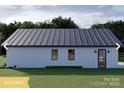 Back of a contemporary farmhouse with white siding, metal roof, and neat landscaping with green lawn at 180 Nc 742 Hwy, Wadesboro, NC 28170