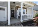 Inviting front porch with stone accents, a welcome sign, and a cozy seating area at 2220 Atwell Glen Ln, Pineville, NC 28134