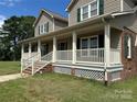 Charming home with a full covered porch, white railing, and green shutters on a sunny day at 2417 Lynwood Dr, Lancaster, SC 29720