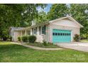 Side view of brick home with a teal garage door, green shutters and well-kept landscaping at 334 Hudson Dr, Harrisburg, NC 28075