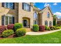 Charming front entrance featuring a brick facade, arched doorway, and vibrant landscaping at 405 Five Leaf Ln, Waxhaw, NC 28173