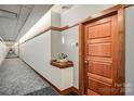 Hallway featuring a wooden doorway, neutral paint, unique patterned carpet, and decorative ledge with subtle lighting at 435 S Tryon St, Charlotte, NC 28202