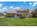 Expansive backyard featuring a brick house, covered patio, lush lawn, and a unique stone garden feature at 4405 3Rd Nw St, Hickory, NC 28601