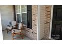 Inviting front porch showcasing chairs for relaxing, brick accents, and a well-manicured exterior at 6222 Meadow Glen Ln, Harrisburg, NC 28075