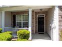Welcoming front porch featuring a cozy sitting area, brick facade, and well-maintained landscaping at 6222 Meadow Glen Ln, Harrisburg, NC 28075