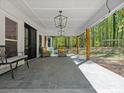 Covered back porch features overhead lighting, stone floors, seating, and backyard views at 6724 Brushwood Dr, Charlotte, NC 28262