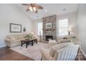 Cozy living room with a stone fireplace, high ceilings, neutral furniture, and a ceiling fan at 8257 Legare Ct, Charlotte, NC 28210