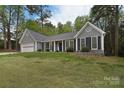 Inviting single-story home with gray siding, black shutters, and mature trees in a serene setting at 9208 Plashet Ln, Mint Hill, NC 28227