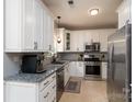 Well-lit kitchen features granite counters, stainless steel appliances, and white cabinets at 13228 Crooked Pine Ct, Charlotte, NC 28215