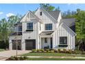 Striking white two-story modern farmhouse with dark trim, black metal roof accents, and a landscaped yard at 14013 Pinoli Pine Cir, Huntersville, NC 28078
