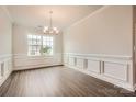 Formal dining room featuring hardwood floors, modern wainscoting, a modern chandelier, and a large window at 1541 Croydon St, Indian Land, SC 29707
