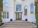 Inviting front entrance with a beautiful door, stone steps, potted plants, and stylish sconces at 1700 White Pond Ln, Waxhaw, NC 28173