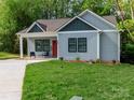 Charming home featuring a well-manicured lawn, inviting front porch, and gray wood siding at 2302 Jordi Way, Charlotte, NC 28213