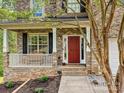 Inviting brick home with a cozy front porch featuring white columns and a vibrant red front door at 3914 Cassidy Dr, Waxhaw, NC 28173