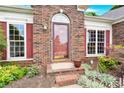 Close-up of brick home entry showcasing a red door and decorative landscaping at 4155 Guilford Nw Ct, Concord, NC 28027