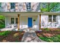 Inviting front porch showcasing a blue front door, white brick, wooden columns, and landscaped flower beds at 4313 Sudbury Rd, Charlotte, NC 28205