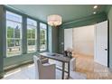 Bright home office with green walls, ample natural light, and a modern desk and seating arrangement at 5010 Ohm Ln, Charlotte, NC 28270