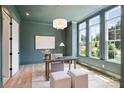 Stylish home office featuring a desk, plush seating, three windows, and light hardwood floors at 5010 Ohm Ln, Charlotte, NC 28270