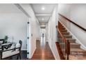 Long hallway with hardwood floors leading to other rooms, staircase with decorative iron railing and light gray walls at 5628 Selkirkshire Rd, Charlotte, NC 28278
