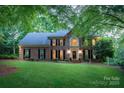 Charming brick home with well-lit windows, a green lawn, and mature trees showcasing a serene residential atmosphere at 6017 Summerston Pl, Charlotte, NC 28277