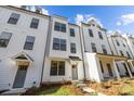 Eye-level exterior shows the front of a three-story modern white townhome with black window trim and a covered porch at 655 District Ct, Fort Mill, SC 29708