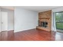 A cozy living room with a brick fireplace, hardwood floors, and a sliding glass door at 10967 Harrowfield Rd, Charlotte, NC 28226