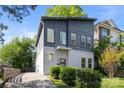 A modern home's exterior featuring stylish gray siding, a concrete driveway, and lush landscaping at 1121 N Alexander St, Charlotte, NC 28206