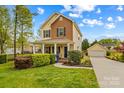 Inviting two-story home with a covered front porch, lush landscaping, and a detached garage at 12746 Bravington Rd, Huntersville, NC 28078