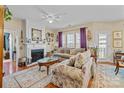 Cozy living room featuring hardwood floors, fireplace, ceiling fan, neutral paint, and large windows at 14869 Santa Lucia Dr, Charlotte, NC 28277