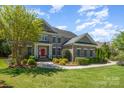 Charming two-story brick home featuring a red front door, manicured landscaping, and a well-maintained lawn at 16636 Flintrock Falls Ln, Charlotte, NC 28278