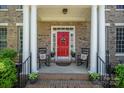 Inviting front porch with red door, rocking chairs, brick accents, and decorative plants, creating a welcoming entrance at 16636 Flintrock Falls Ln, Charlotte, NC 28278
