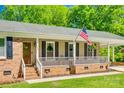 Close-up view of a brick-lined front porch with an American flag, white railings, and wood trim at 1938 Hickory Dr, Lancaster, SC 29720