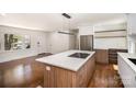 Modern kitchen with stainless steel appliances, island cooktop, and sleek white cabinetry at 2014 Sandhurst Dr, Charlotte, NC 28205