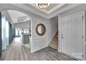 Inviting foyer featuring a staircase, modern flooring, decorative mirror, and an open view to the kitchen at 314 Wave Crest Dr, Tega Cay, SC 29708