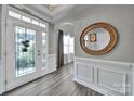 Elegant foyer with decorative glass door, stylish flooring, wainscoting, and a round mirror at 314 Wave Crest Dr, Tega Cay, SC 29708