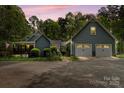 This cozy home has a two-car garage, set amidst a backdrop of mature trees at dusk at 705 Normandy Rd, Mooresville, NC 28117