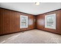 Room featuring neutral carpet, wood paneling, and natural light from multiple windows at 71 14Th Se St, Hickory, NC 28602
