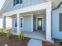 Inviting front porch with sturdy white columns, a modern black front door, and well maintained landscaping at 7185 Chamberlain Dr, Harrisburg, NC 28075