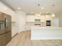 Spacious kitchen featuring white cabinetry, stainless steel appliances, and an island with quartz countertop at 7185 Chamberlain Dr, Harrisburg, NC 28075