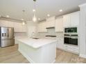 Bright kitchen featuring white cabinetry, stainless steel appliances, and an island with quartz countertop at 7185 Chamberlain Dr, Harrisburg, NC 28075