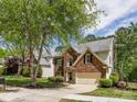 Charming two-story brick home with attached two-car garage and mature trees in a well-maintained lawn at 7409 Tarland Ln, Charlotte, NC 28269