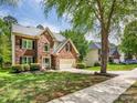 Beautiful two-story brick home features a well-manicured lawn, mature trees, and an attached two-car garage at 7409 Tarland Ln, Charlotte, NC 28269
