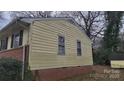 This yellow home features a brick foundation, and two windows on the side at 828 Williams St, Gastonia, NC 28052