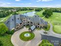 Expansive aerial view of estate home overlooking golf course, lake with fountain, and lush green landscape at 8710 Chewton Glen Dr, Waxhaw, NC 28173