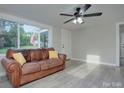 Inviting living room with natural light, a brown leather sofa, and modern ceiling fan at 103 Moore Ave, Mount Holly, NC 28120